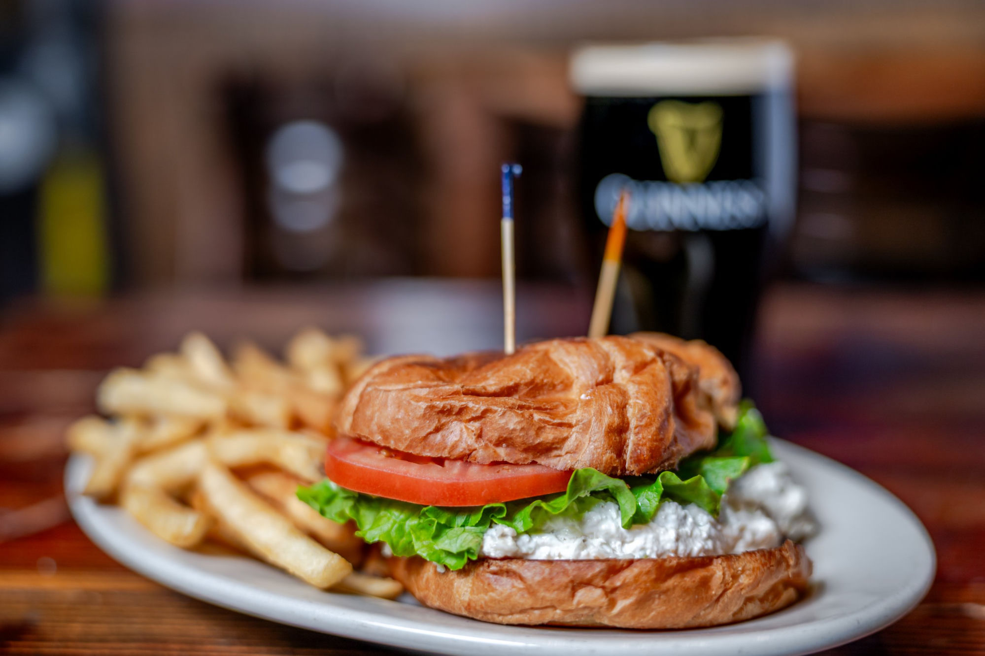 Croissant chicken sandwich with fries and Guinness