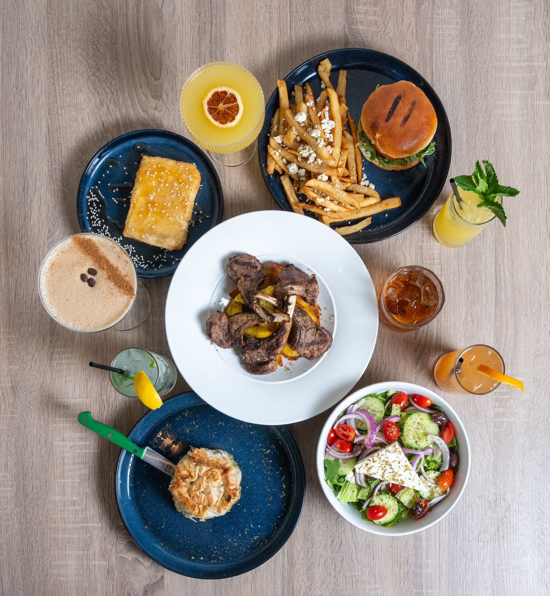 Greek restaurant flat lay with lamb, spanakopita, and salad